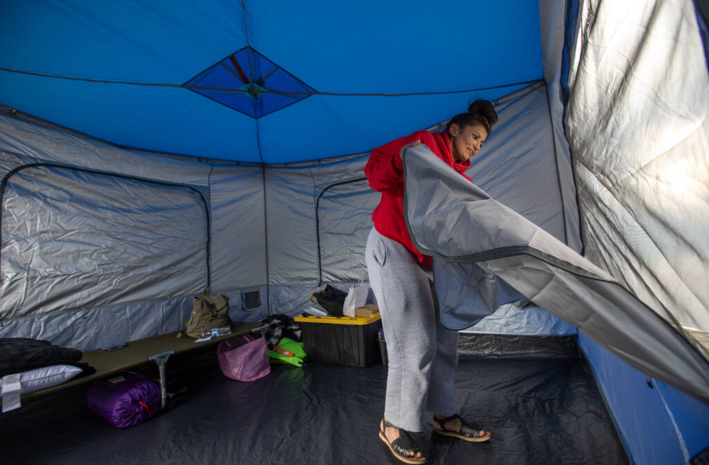 Amanda Negrete opens a window as she settles into her tent after being moved off the Joe Rodota Trail and into a tent camp at the Sonoma County government complex parking lot at Administration Drive and Paulin Drive in Santa Rosa, Wednesday, March 22, 2023. (Chad Surmick / The Press Democrat)
