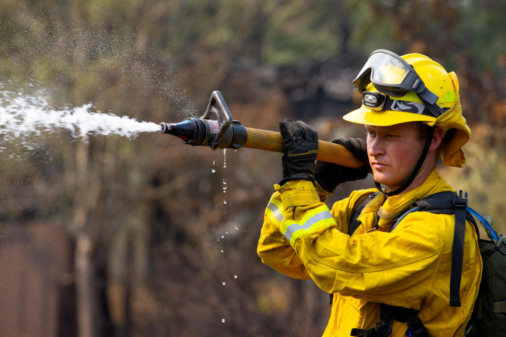 Tiburon firefighter Zac Durall extinguishes hot spots in the backyard of a home on Mountain Hawk Drive after the Glass fire blazed through the Skyhawk Community of Santa Rosa on Tuesday, Sept. 29, 2020. (Alvin A.H. Jornada / The Press Democrat)
