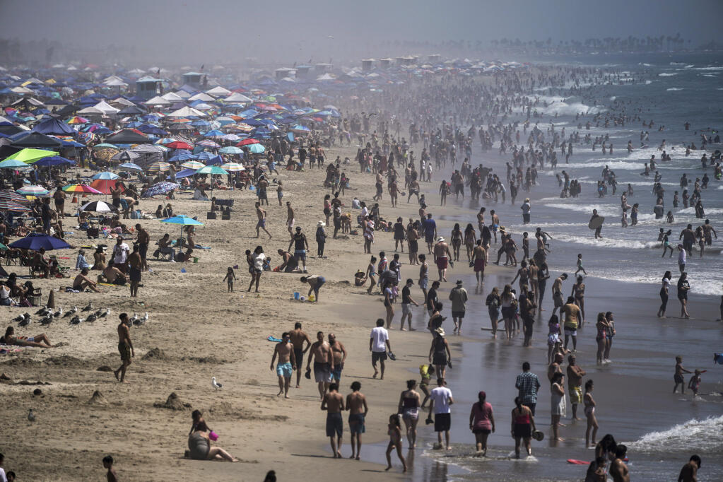 People crowd the beach in Huntington Beach on Sept. 5, 2020. The summer travel season is predicted to finish strong in the North Bay and throughout the state. Area hotels are reporting they are full or nearly full for the last holiday period of the summer and motel-hotels in California are exceeding bookings in pre-pandemic 2019 for the Labor Day weekend, according to the Northern California AAA. (Jae C. Hong / Associated Press)