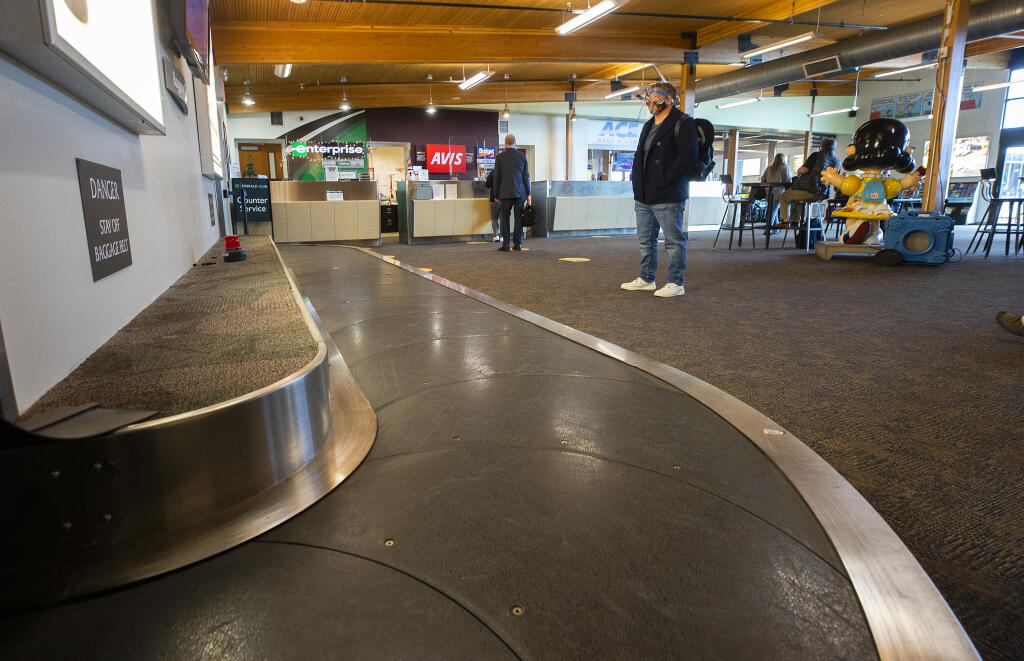 A single passenger waits at the luggage carousel at the Charles M. Schulz-Sonoma County Airport in December. (John Burgess / The Press Democrat) 2020