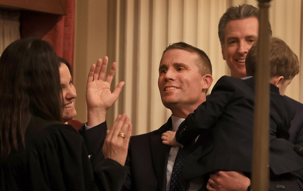 Holding his son, Connor, Sen. Mike McGuire of Healdsburg is sworn in as the 49th Senate President Pro Tempore of California, Monday, Feb. 5, 2024, in Sacramento. At left is his wife, Erika, in the background is California Gov. Gavin Newsom. (Kent Porter / The Press Democrat)