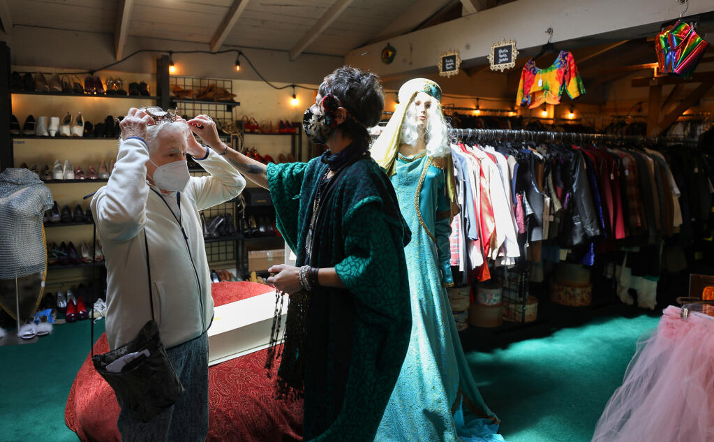 Heather DeYoung, right, helps Barbara Riley try on a crown at Disguise the Limit costume shop in Santa Rosa on Friday, April 23, 2021.  (Christopher Chung/ The Press Democrat)