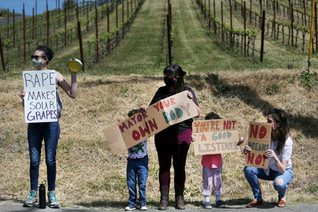 (From left) Angela M., Benji Henderson, 5, his mother Sophia Williams, his sister Gracie Henderson, 4, and Lea Ritter protest Windsor mayor Dominic Foppoli at his family's winery, Christopher Creek Winery, in Healdsburg on Sunday, April 11, 2021. (Beth Schlanker/ The Press Democrat)