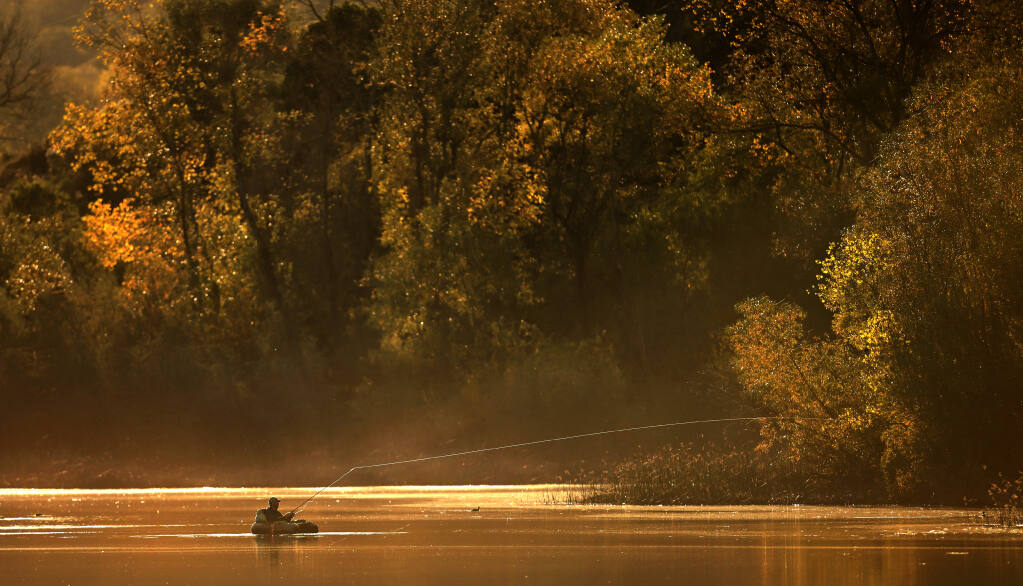 Late afternoon sunlight bathes a fisherman at Lake Wilson in Riverfront Regional Park near Windsor, Friday, Nov. 12, 2021.  (Kent Porter / The Press Democrat) 2021