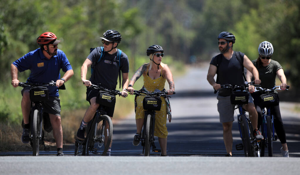 From left, Sonoma Adventures guide Trev Cherry, Salt Lake City residents Russ Knezic and Chelsea Nelson and San Francisco residents Jerry Kamali and Shannon Cosgrove wait for traffic to pass as they take a bike tour of wineries in the Sonoma Valley, Friday, May 28, 2021. (Kent Porter / The Press Democrat) 2021