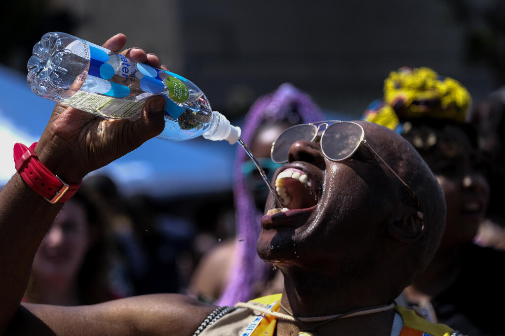 A man drinks a bottle of water in the heat during a Juneteenth commemoration at Leimert Park Plaza on Saturday, June 19, 2021, in Los Angeles. (AP Photo/Ringo H.W. Chiu)