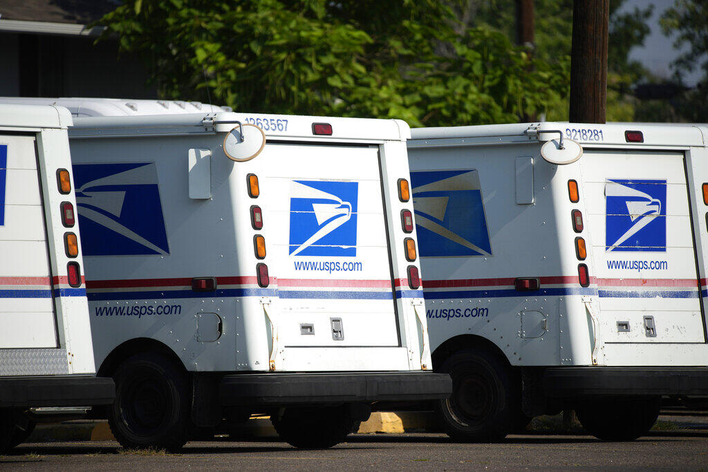 FILE - United States Postal Service delivery vans sit outside a post office in Greeley, Colo., July 26, 2021. (AP Photo/David Zalubowski, File)