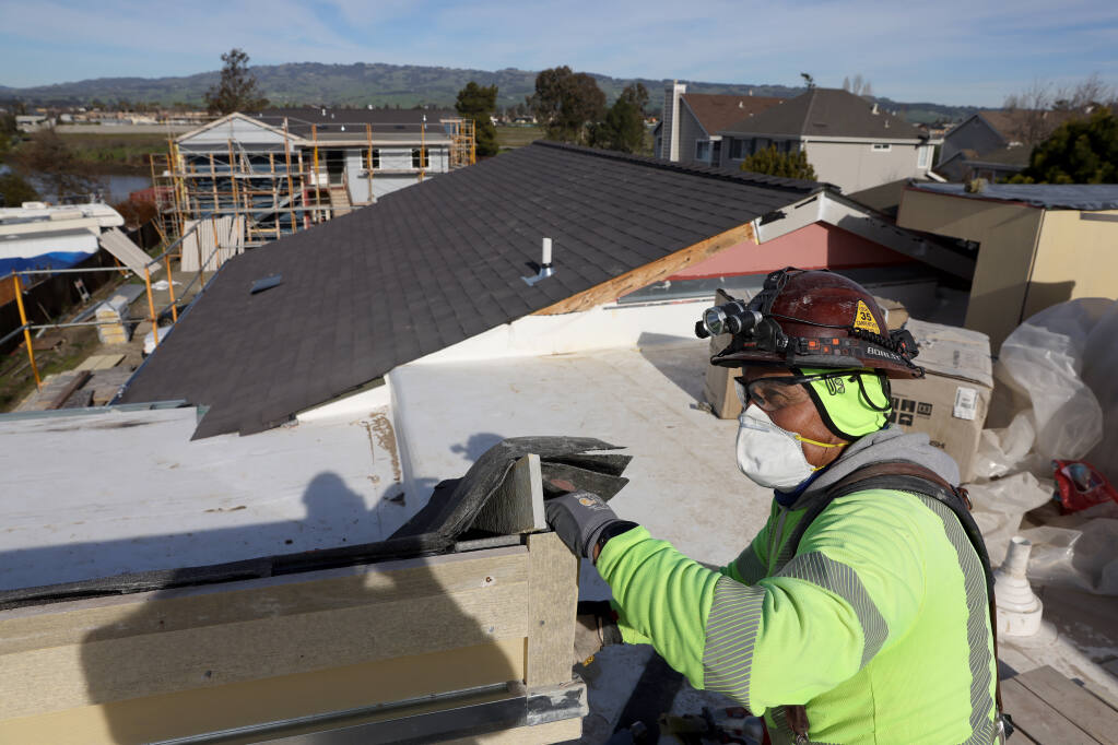 Construction worker Elias Velazquez installs trim on the roof at the River City Senior Apartments, a new PEP Housing residential complex in Petaluma on Jan. 13. (Beth Schlanker/The Press Democrat)