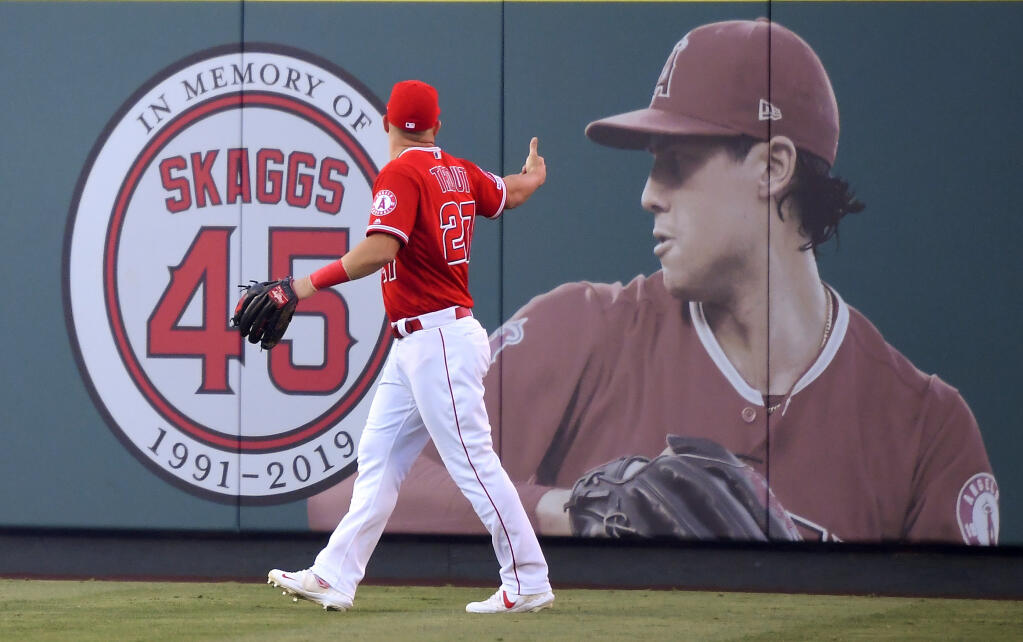 FILE - Los Angeles Angels center fielder Mike Trout gestures toward a photo of Tyler Skaggs in center field prior to a baseball game against the Detroit Tigers in Anaheim, Calif., on July 29, 2019. Former Los Angeles Angels employee Eric Kay was sentenced to 22 years in federal prison on Tuesday, Oct. 11, 2022, for providing Angels pitcher Tyler Skaggs the drugs that led to his overdose death in Texas. (AP Photo/Mark J. Terrill, File)