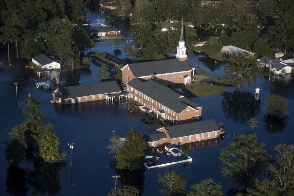 FILE - In this Monday, Sept. 17, 2018 file photo, floodwaters surround a church and other buildings in Conway, S.C., after Hurricane Florence struck the Carolinas. According to a study released on Wednesday, Nov. 11, 2020, hurricanes are keeping their staying power longer once they make landfall, spreading more inland destruction. (AP Photo/Sean Rayford)