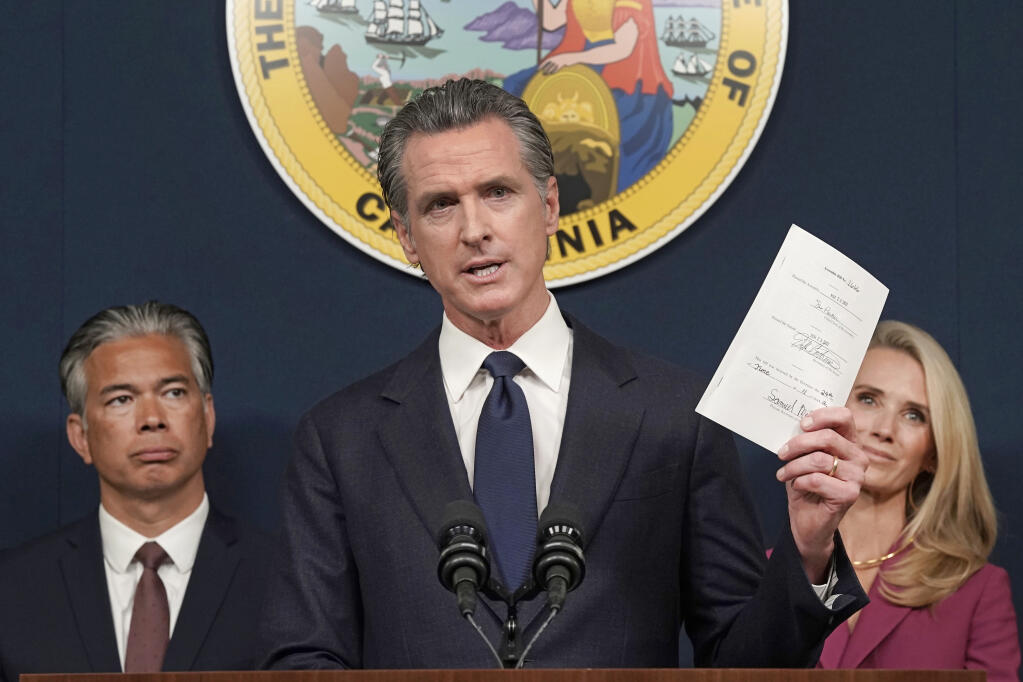 FILE – California Gov. Gavin Newsom displays a state bill signed by him shielding abortion providers and volunteers in California from civil judgments from out-of-state courts during a news conference in Sacramento, Calif., June 24, 2022. (AP Photo/Rich Pedroncelli, File)