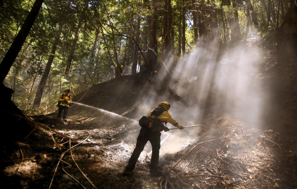 Steve Frazier, right, of Cal Fire's Cazadero station and Monte Rio firefighter Matt Simmons, extinguish hot spots on a fire off Bohemian Highway in Monte Rio, Wednesday, August 5, 2020. (Kent Porter / The Press Democrat) 2020