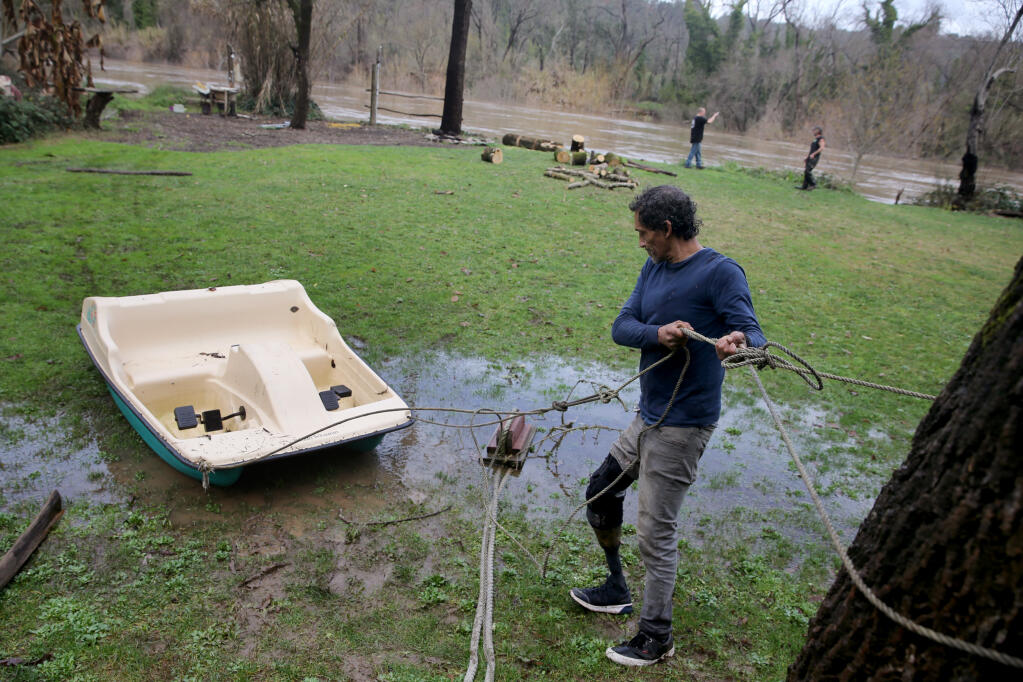 Carlos Frutis secures a paddle boat in preparation for flooding at his friend's property on the banks of the Russian River in Forestville, Calif., Sunday, Jan. 8, 2023. (Beth Schlanker/The Press Democrat file)