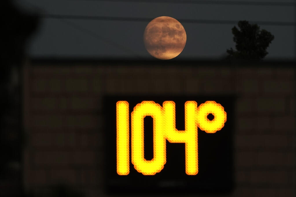 A temperature of 104 degrees is displayed on a digital thermometer as the moon rises over Sacramento, Calif., Thursday, Sept. 8, 2022. A heat wave setting several high temperature marks in California. (AP Photo/Rich Pedroncelli)