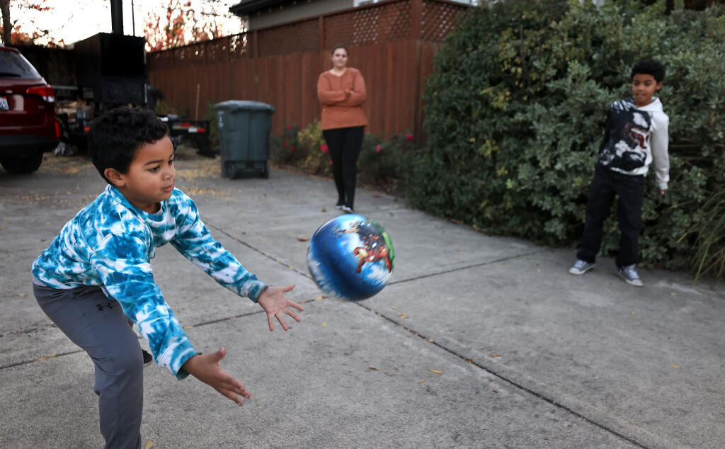 Elijah Austin, 5, left, and brother Isaiah, 8, play four square with neighborhood kids (not pictured) Friday, Nov. 18, 2022, outside their home in Santa Rosa as mom Tyanna Austin supervises. Elijah was down for almost a month, with high fevers and flu symptoms including an nearly unshakable cough. (Kent Porter / The Press Democrat) 2022