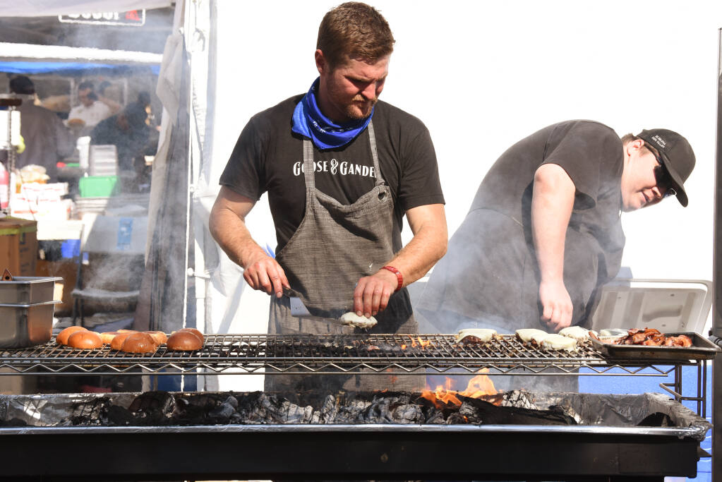 Jesse Frate, left, and Matt Daugherty grilling burgers on a mesquite grill for Goose & Gander during BottleRock Napa Valley in Napa, California on Friday, September 3, 2021. (Photo: Erik Castro/for The Press Democrat)