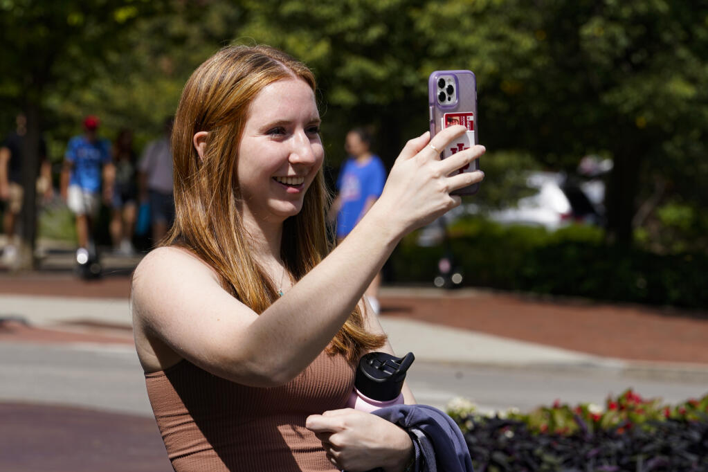 Emily Korenman, freshman, 18, from Dallas, takes a photo of her parents at the Sample Gates at Indiana University in Bloomington, Ind., Tuesday, Aug. 16, 2022. (AP Photo/Michael Conroy)