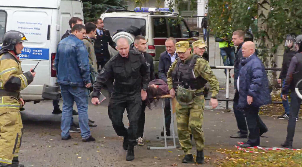 In this image taken from video, servicemen carry a wounded person from the scene of a shooting at school No. 88 in Izhevsk, Russia, Monday, Sept. 26, 2022. (Izhlife.ru via AP)