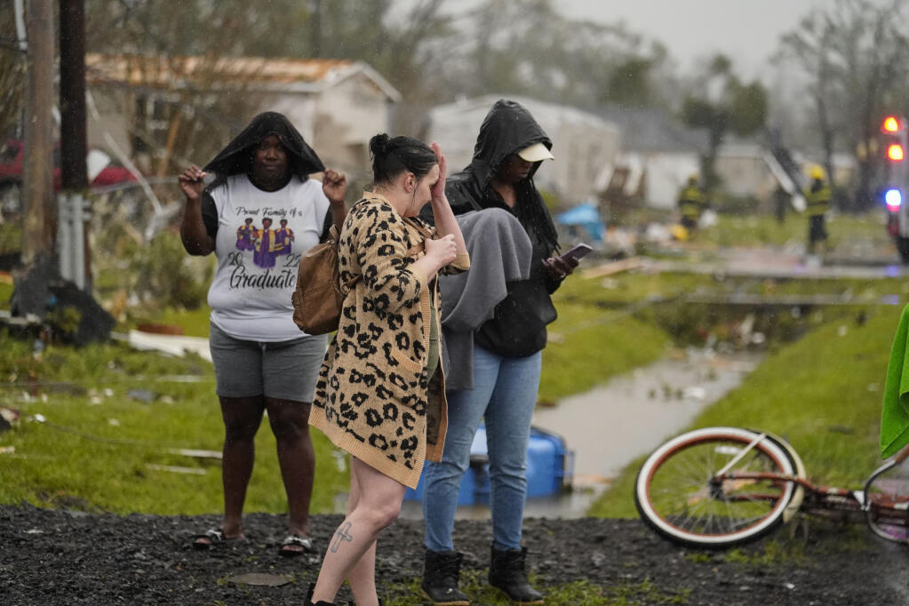 Residents stand outside destroyed homes from a tornado that tore through the area in Killona, La., about 30 miles west of New Orleans in St. James Parish, Wednesday, Dec. 14, 2022. (AP Photo/Gerald Herbert)
