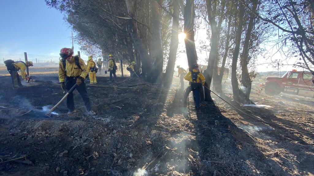 Crews tend to hot spots Friday at the scene of a 15-acre fire that ignited just after 4 p.m. north of Petaluma. (Kent Porter / The Press Democrat)