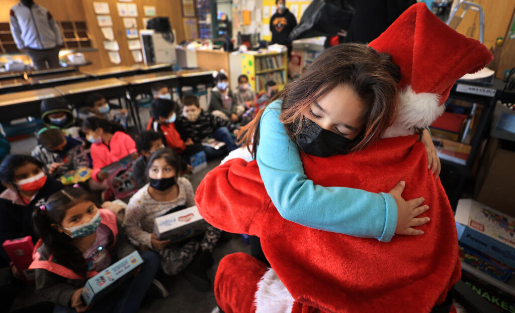 First grader Danna Mora gives a hug of thanks to Piner High School  ASB student Santa, Andy Wiggins, after a receiving a gift ,Thursday, Dec. 9, 2021 at Monroe Elementary School in Santa Rosa   (Kent Porter / The Press Democrat) 2021