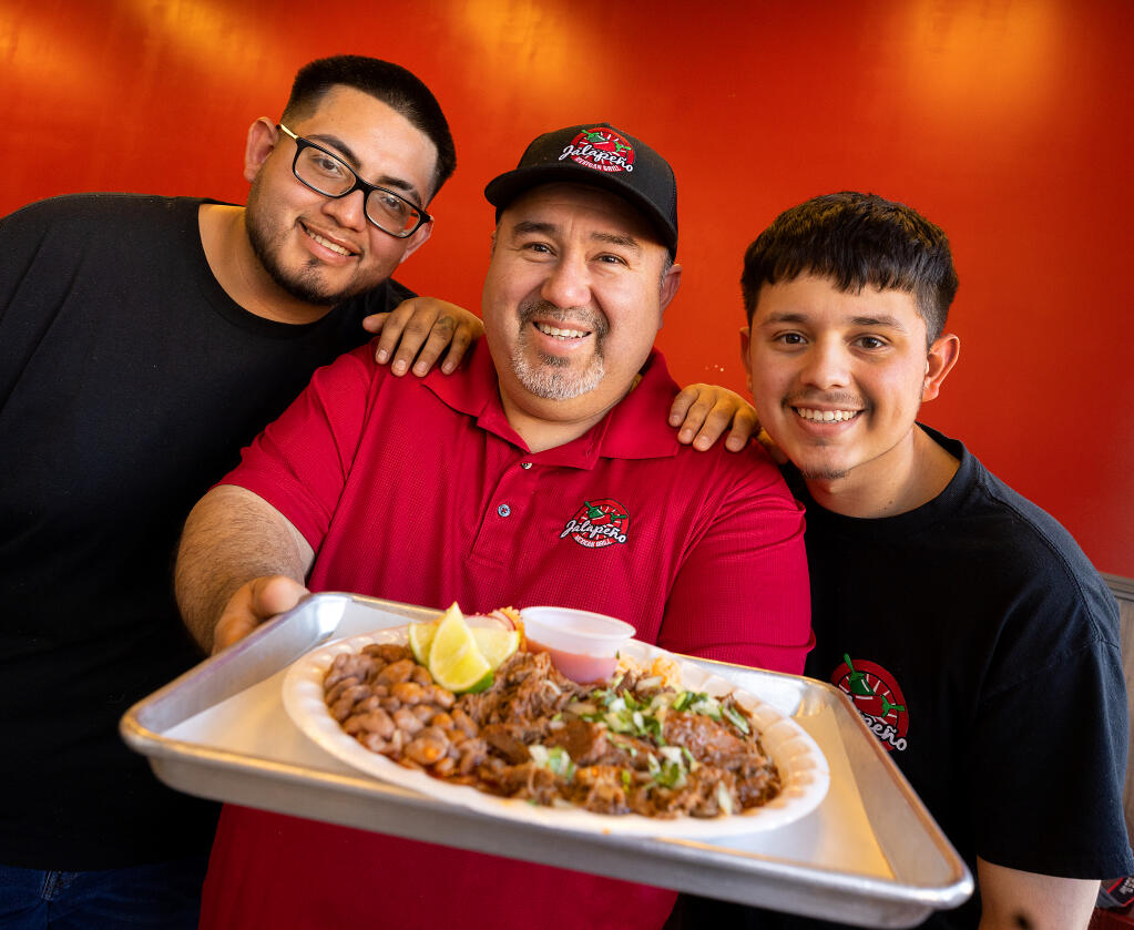 Jalapeño Mexican Grill owner Gustavo Cazares, center, with his sons Gustavo Jr. left, and Jonny with a plate of their house specialty Birria, Wednesday, Jan. 25, 2023. (John Burgess/The Press Democrat)