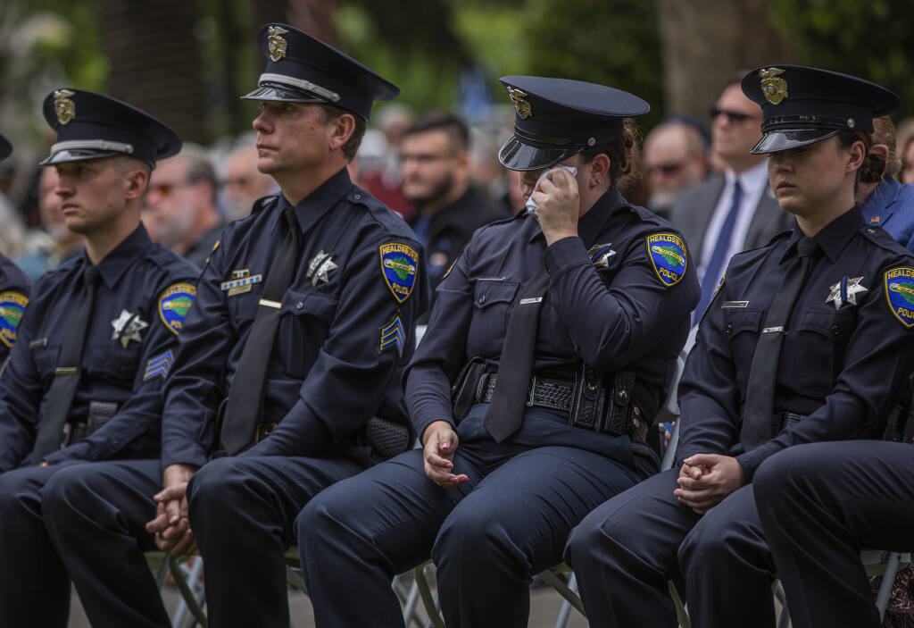 Healdsburg Police officer Morgan Dudley wipes away tears while viewing a slide show during the celebration of life for Police Chief Kevin Burke at the Healdsburg plaza in downtown Healdsburg May 6, 2022. (Chad Surmick / The Press Democrat)