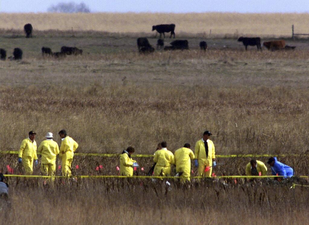 FILE - A crew of workers supervised by the National Transportation Safety Board place flags among the wreckage of a private jet transporting Payne Stewart in a farm field near Mina, S.D., Oct. 26, 1999. Some aviation experts are citing pilot hypoxia as a leading theory for why an unresponsive business plane flew over the nation’s capital on Sunday, June 4, 2023, and caused the military to scramble fighter jets. One of the most well-known crashes involving hypoxia was the 1999 crash of a Learjet that lost cabin pressure and flew halfway across the country on autopilot before running out of gas and crashing in a South Dakota pasture, killing professional golfer Stewart and five others. (AP Photo/Dave Weaver, File)