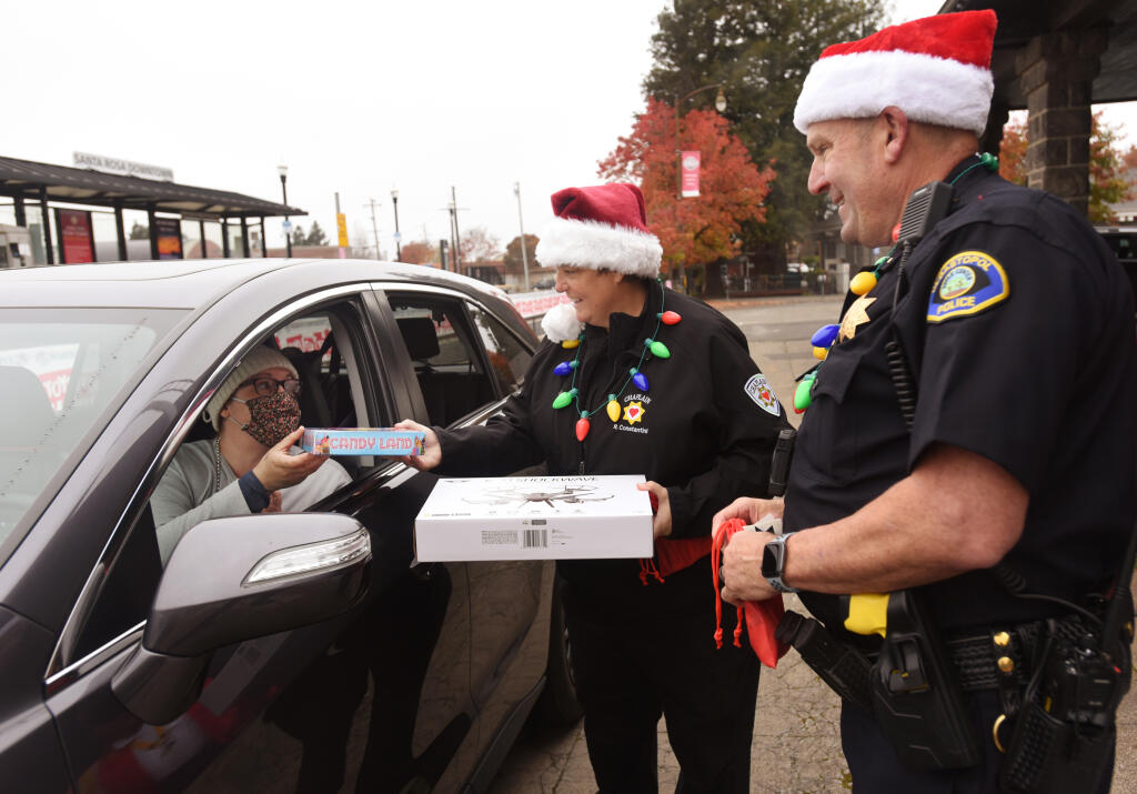 Allison Angel Funk, left, handing over donated gifts to Sonoma County Executive Director of Law Enforcement Chaplain Rita Constantini, center, and Lieutenant Ron Nelson of Sebastopol Police Department during the 6th annual Holiday Express Toys for Tots Drive held in Railroad Square at the downtown Santa Rosa SMART station in Santa Rosa, Calif., on Saturday, December 4, 2021. (Photo: Erik Castro/for The Press Democrat)