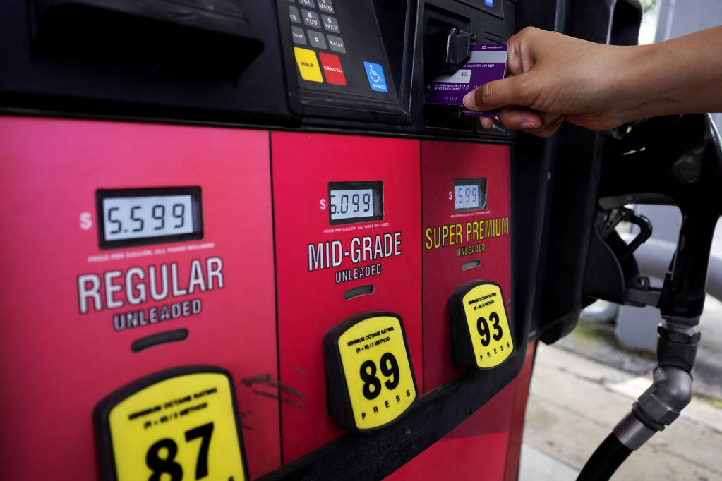 A customer holds a credit card at the pay-at-the-pump gasoline pump in Rolling Meadow, Illinois, Thursday, June 30, 2022. (Nam Y. Huh / The Associated Press)