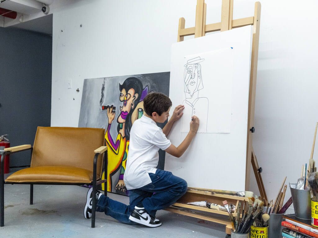 Andres Valencia sketches a piece in a basement studio of the Chase Contemporary Gallery in the SoHo neighborhood of New York, where his art was exhibited this summer, Aug. 1, 2022. Valencia’s paintings have sold for more than $125,000 — and he’s 10 years old. (Elliott Jerome Brown Jr./The New York Times)
