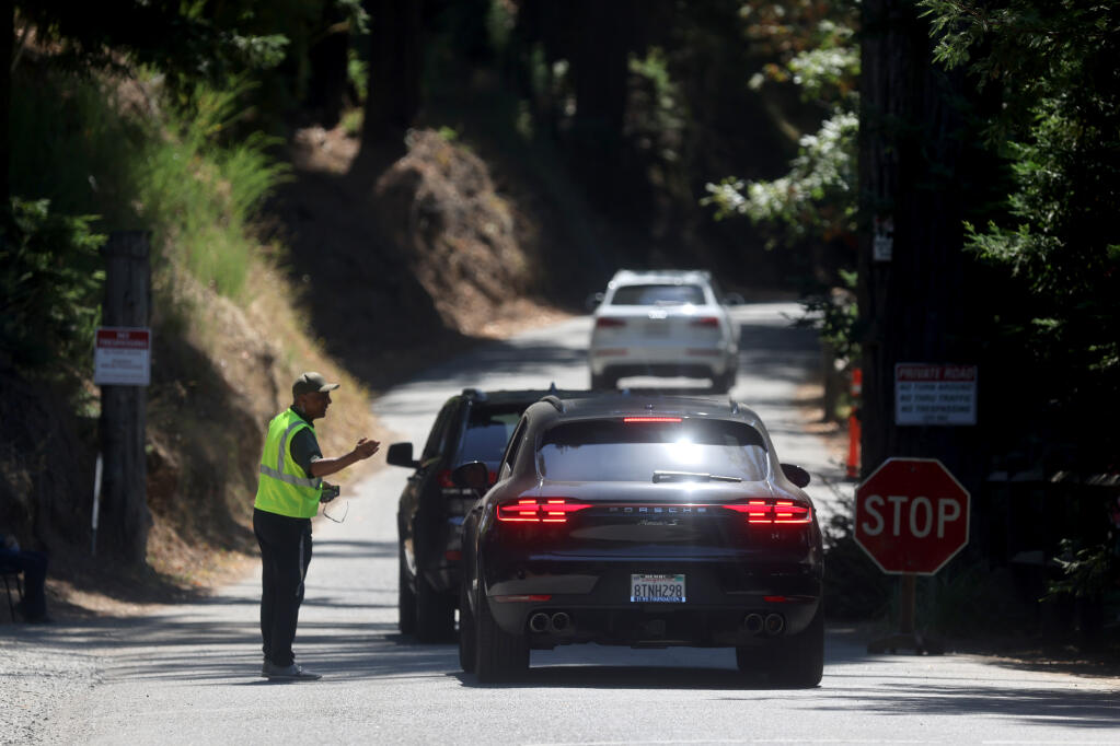 A security guard talks with a driver at the main entrance of Bohemian Grove in Monte Rio, Thursday, July 28, 2022. (Beth Schlanker / The Press Democrat file)
