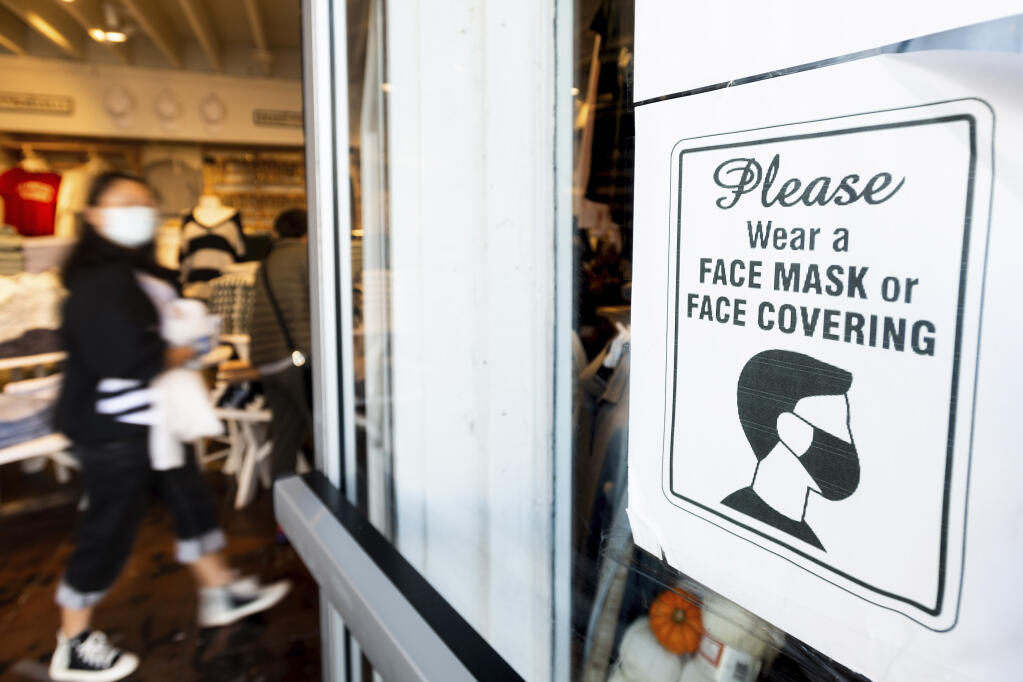 A shopper passes a sign urging customers to wear masks at a Brandy Melville store on Wednesday, Oct. 21, 2020, in San Francisco. (AP Photo/Noah Berger)