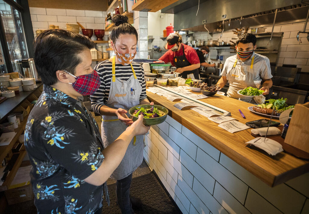 Geneva Melby, center, chef du cuisine at Khom Loi restaurant in Sebastopol hands off a dish to server Chris Chester on Thursday, Aug. 5, 2021. Now she and her husband, Ryan Miller, are set to open The Redwood, a natural wine bar, this month. (John Burgess/The Press Democrat)