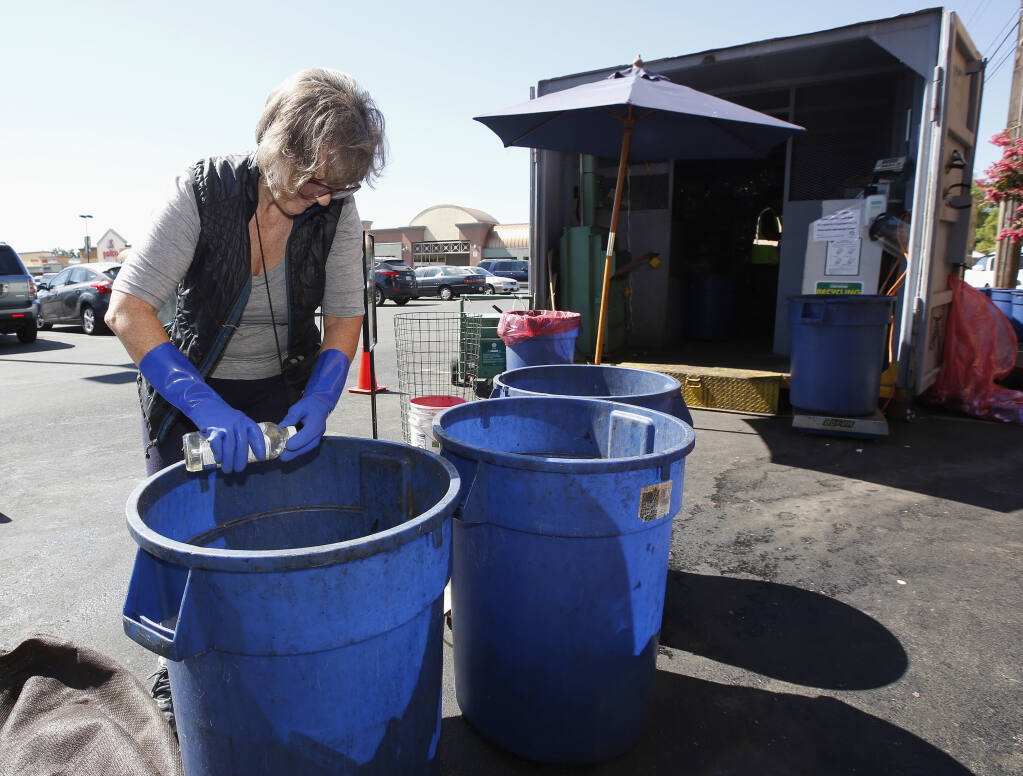 FILE - In this Tuesday, July 5, 2016, file photo, Claudette Cole places a plastic bottle into a plastic container for recycling at a recycling center in Sacramento, Calif. Californians will have a better idea of what's headed for landfills instead of recycling centers under one of several related bills that Gov. Gavin Newsom signed into law Tuesday, Oct. 5, 2021. It sets the nation's strictest standards for which items can display the “chasing arrows” recycling symbol, advocates say. (AP Photo/Rich Pedroncelli, File)