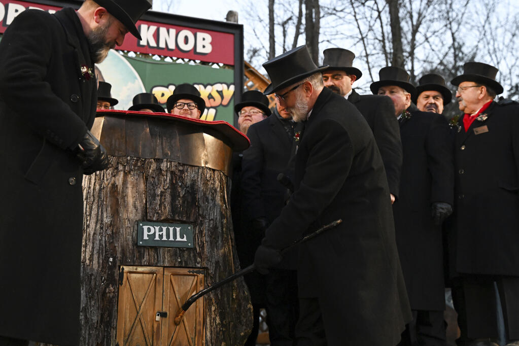 Groundhog Club Vice President Tom Dunkel taps on the burrow of Punxsutawney Phil, the weather prognosticating groundhog, during the 137th celebration of Groundhog Day on Gobbler's Knob in Punxsutawney, Pa., Thursday, Feb. 2, 2023. Phil's handlers said that the groundhog has forecast six more weeks of winter. (AP Photo/Barry Reeger)
