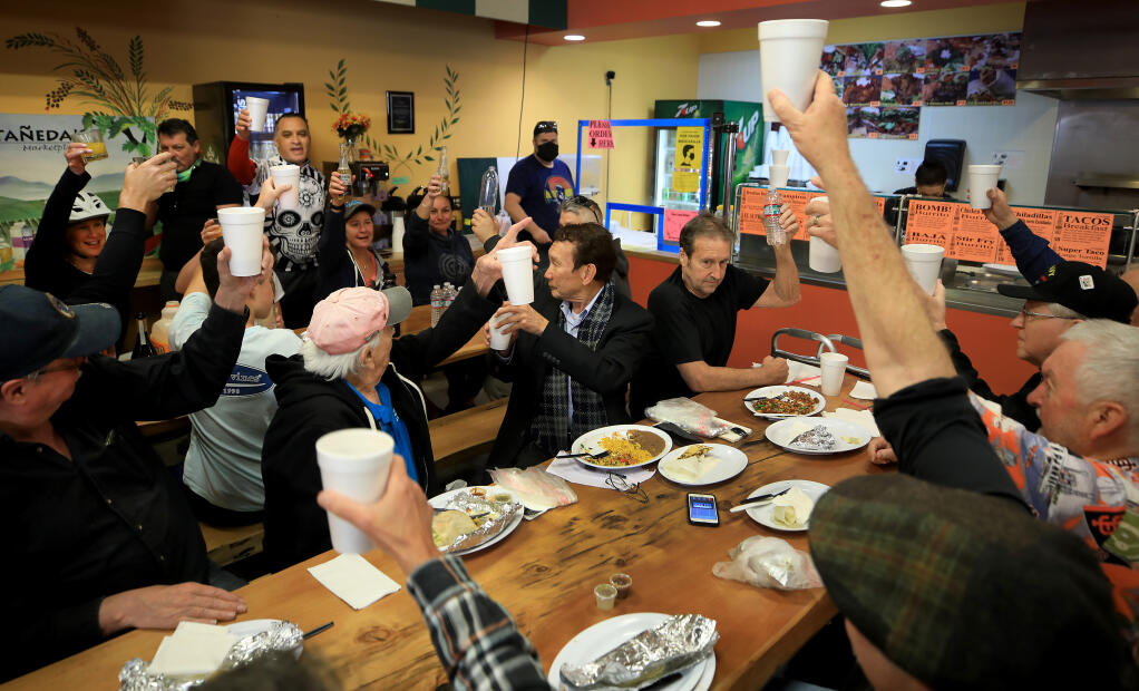 Castañeda’s Marketplace owner José Castañeda, in bike shirt with red sleeves, and his riding partners, toast military veterans from left clockwise, Rob Geidl, Harold Goldman, Norman Birkenstock, Bill Robinson, Del Wolverton, Gary Coopersmith and Steve Henrickson, during the veterans Saturday morning breakfast at the market in Windsor, May 22, 2021. Castañeda has been hosting the vets for 10 years.  (Kent Porter / The Press Democrat)