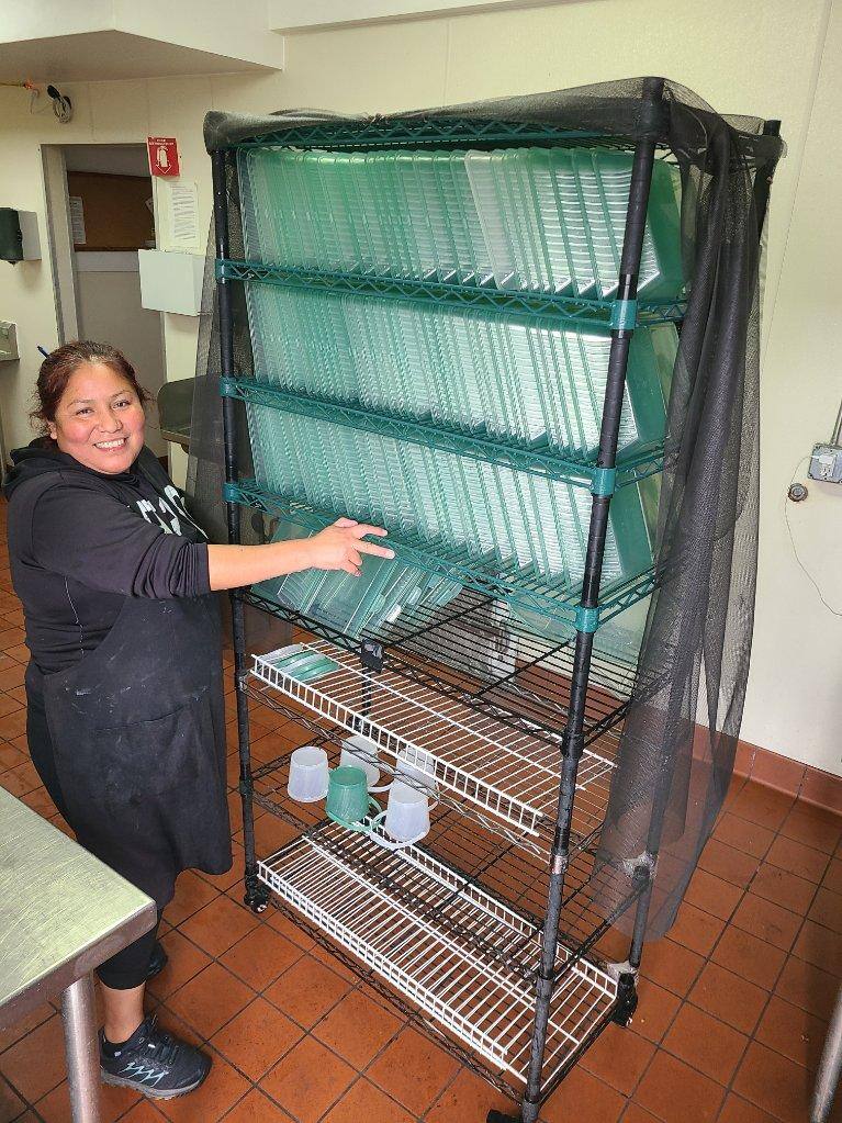 An employee with Sparkl poses with a drying rack full of washed and sanitized returned takeout containers. (courtesy of Sparkl)