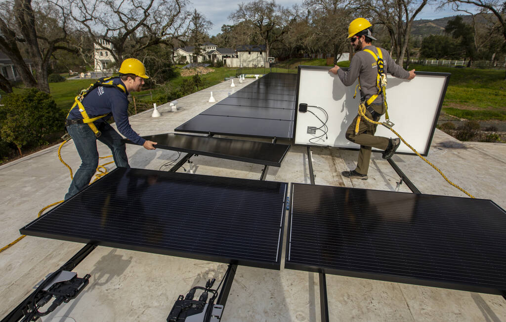Solar panel installer Laird Whisman, right, of First Response Solar, carries a 354 watt solar panel into place while installer Brian Britton, left, moves a panel out of the way while installing a new system at a home in Glen Ellen on Friday, Jan. 28, 2022. (Chad Surmick / The Press Democrat)