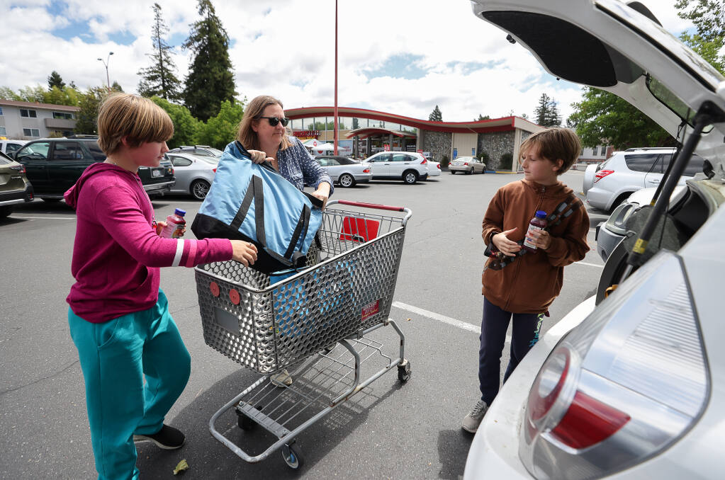 Liesel Hall, center, loads groceries into her car with the help of two of her five children, Monique, 9, left, and Felicity, 11, at Grocery Outlet in Santa Rosa on Friday, June 17, 2022.  (Christopher Chung/The Press Democrat)