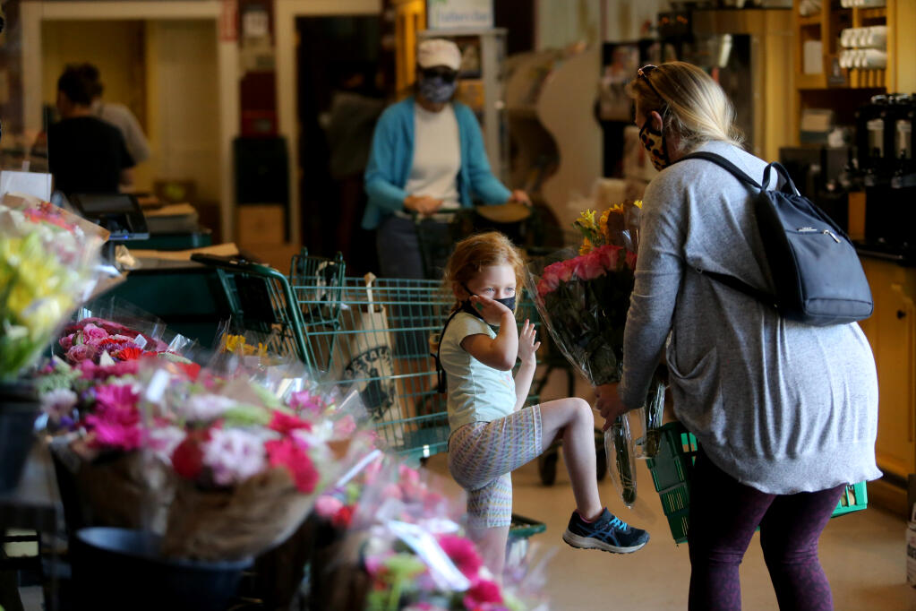 Danielle Richard and daughter Callie, 7, shop for flowers at Petaluma Market in Petaluma, Calif., on Tuesday, June 15, 2021. Despite there being no requirement to wear masks, Danielle Richard feels its only fair to wear her mask since her daughter is still unvaccinated. (Beth Schlanker/The Press Democrat)