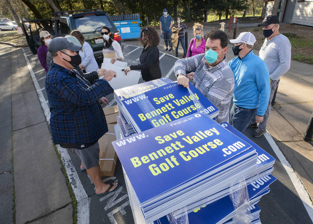 Golfers lined up in their cars to pick up some of the 400 signs in support of the Bennett Valley Golf course in the parking lot of the course on Friday, Feb.19, 2021.  (John Burgess/The Press Democrat)