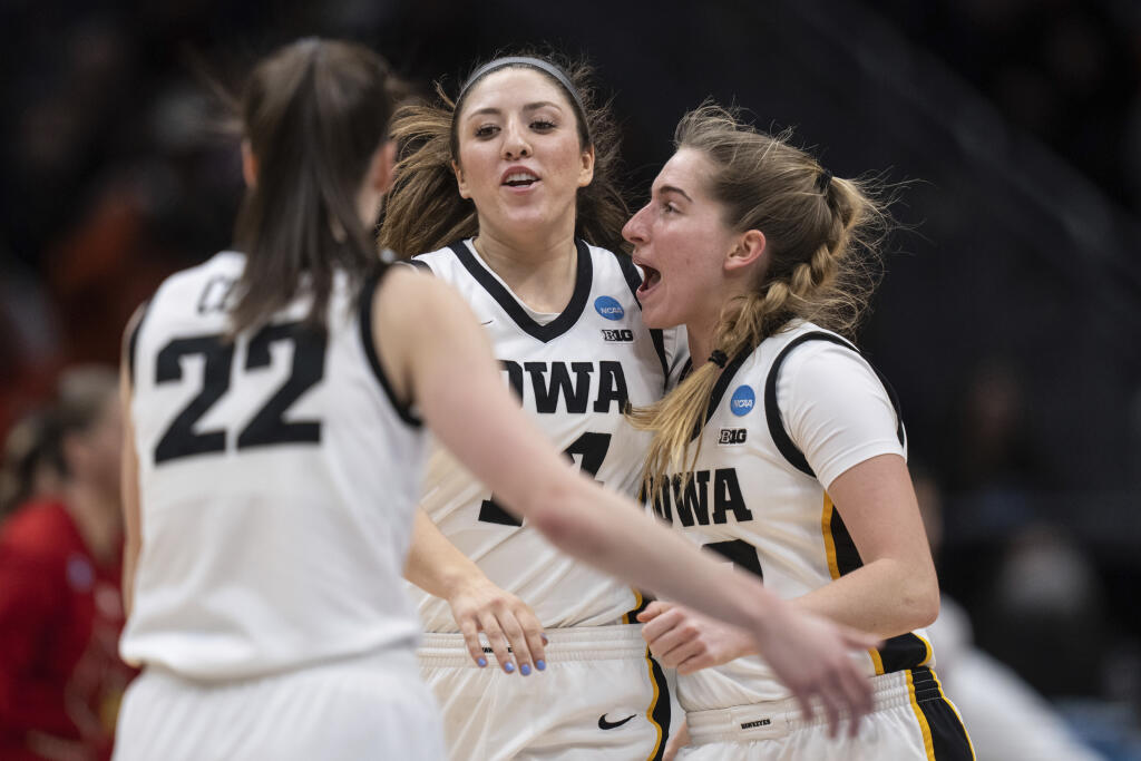 Iowa forward McKenna Warnock, center, guard Caitlin Clark (22) and guard Kate Martin, right, celebrate during the first half of an Elite 8 college basketball game of the NCAA Tournament against Louisville, Sunday, March 26, 2023, in Seattle. (AP Photo/Stephen Brashear)