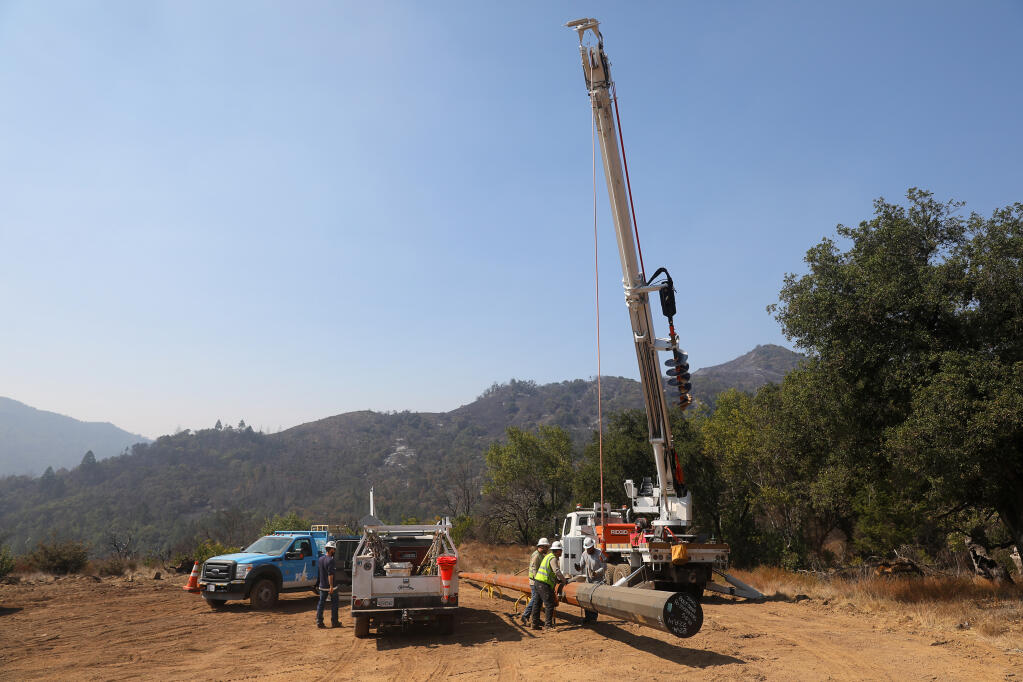 A PG&E crew works on installing a new power pole, to replace one burned in the Glass fire, near the Gray Pine Trail in Sugarloaf Ridge State Park on Monday, Oct. 5, 2020.  (Christopher Chung / The Press Democrat)