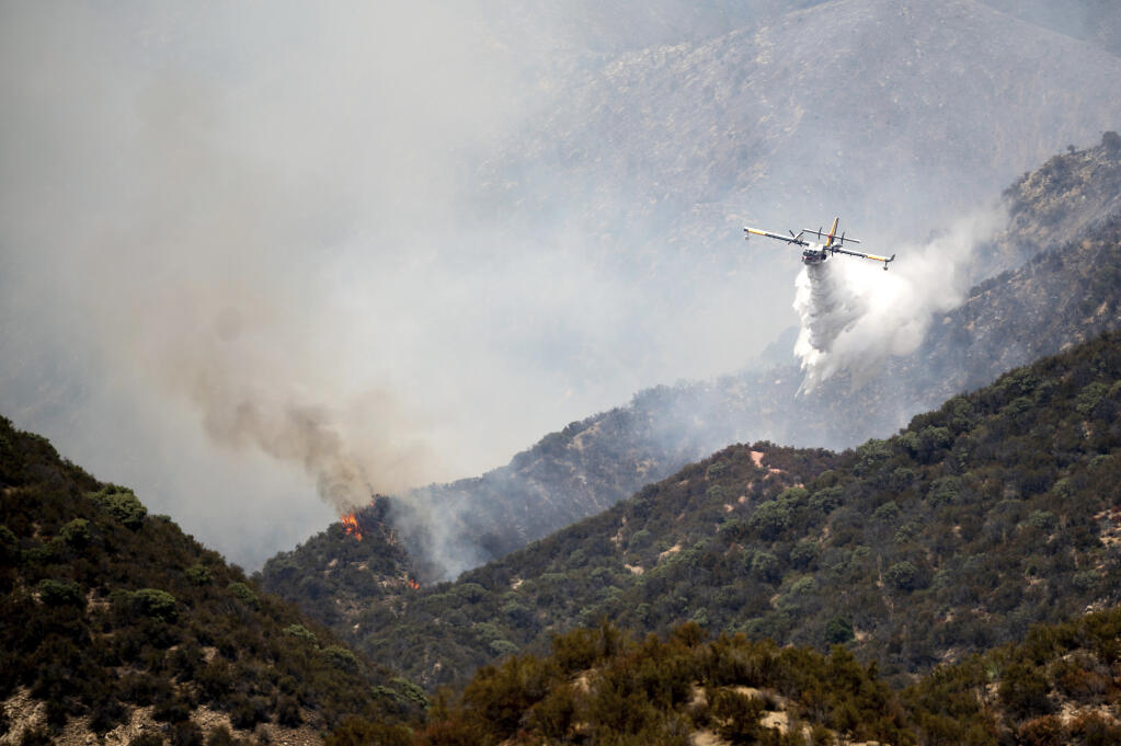 A super scooper drops water to stop the Lake Fire from spreading in the Angeles National Forest north of Santa Clarita, Calif., on Thursday, Aug. 13, 2020. (AP Photo/Noah Berger)