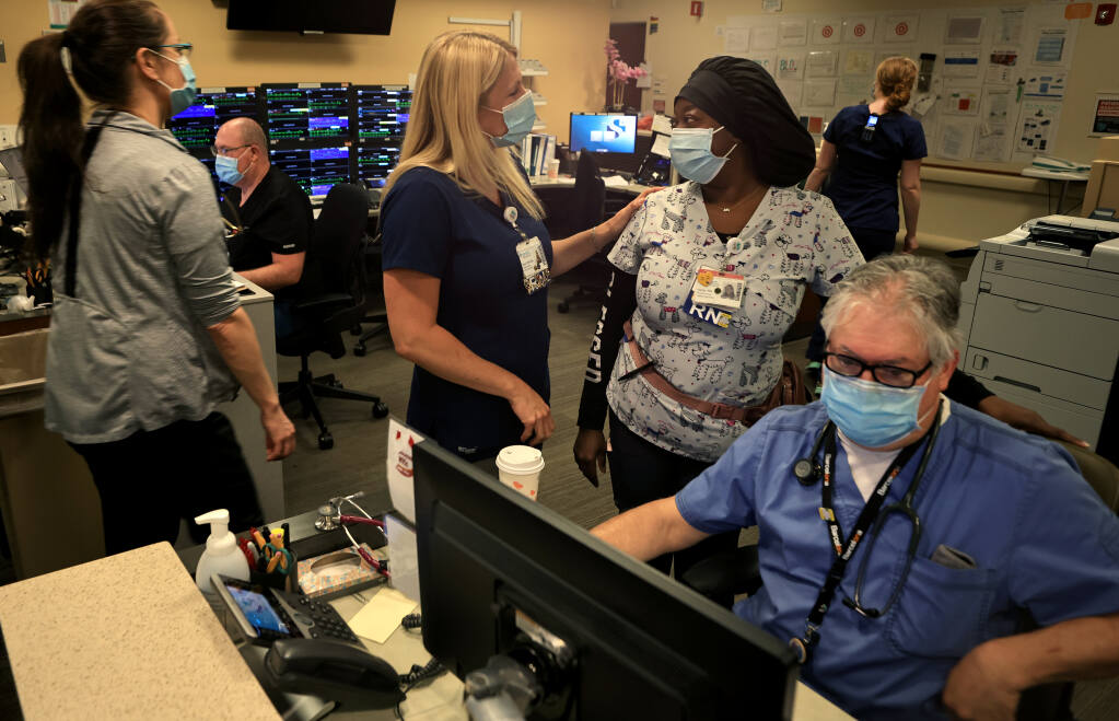 Registered nurses Sara Fisher, middle left, and Alicia Prime greet one another as registered nurse Eric Cullen prepares paperwork. Tuesday, June 22, 2021, in what was once a COVID-19-dedicated ICU ward at Sutter Santa Rosa Regional Hospital.  (Kent Porter / The Press Democrat) 2021
