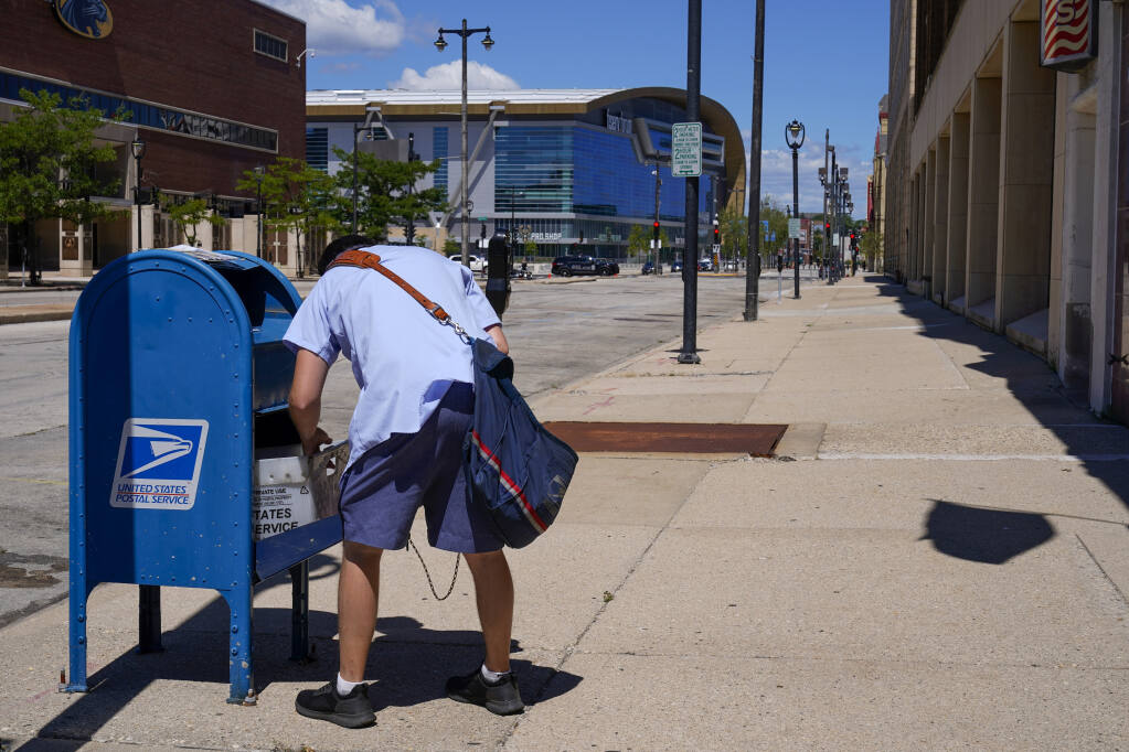 A postal worker empties a box Tnear the Fiserv Forum Tuesday, Aug. 18, 2020, in Milwaukee. (AP Photo/Morry Gash)