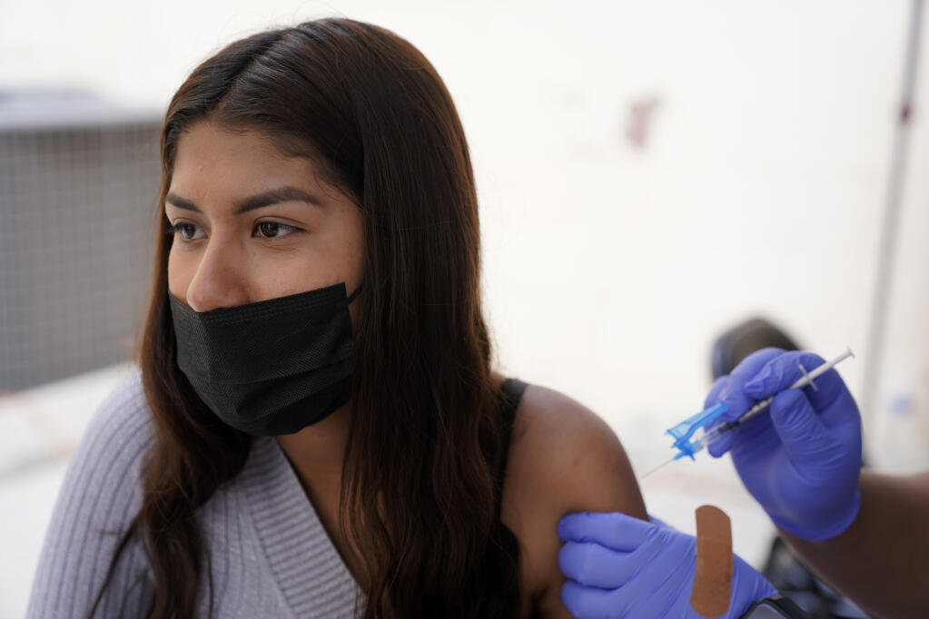 A young woman from Tijuana, Mexico, receives a vaccination shot against the coronavirus outside of the Mexican Consulate building, Thursday, Nov. 18, 2021, in San Diego. Scores of Mexican adolescents were bused to California on Thursday to get vaccinated against the coronavirus as efforts get underway across Mexico to get shots in the arms of teens. (AP Photo/Gregory Bull)