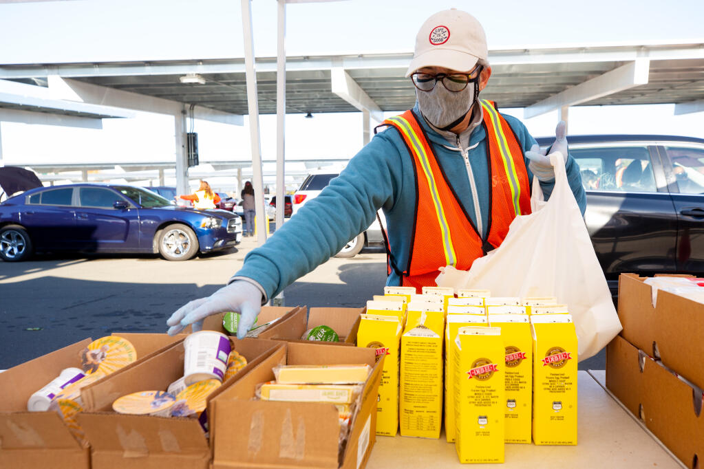 Volunteer Mary Seggerman bags dairy products for recipients during a Redwood Empire Food Bank food distribution at Kaiser Permanente in Santa Rosa on Saturday, Nov. 21, 2020. (Alvin A.H. Jornada / The Press Democrat)
