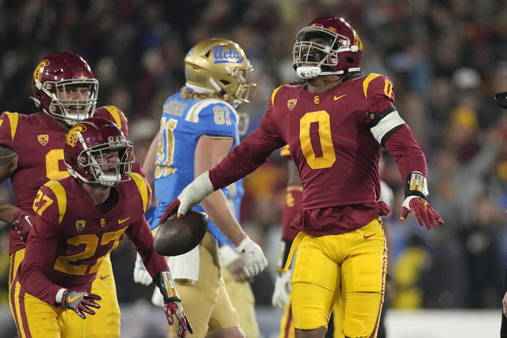Southern California defensive end Korey Foreman, right, celebrates with defensive back Bryson Shaw, second from left, and defensive lineman Brandon Pili after intercepting a pass during the second half of an NCAA college football game against UCLA Saturday, Nov. 19, 2022, in Pasadena, Calif. (AP Photo/Mark J. Terrill)